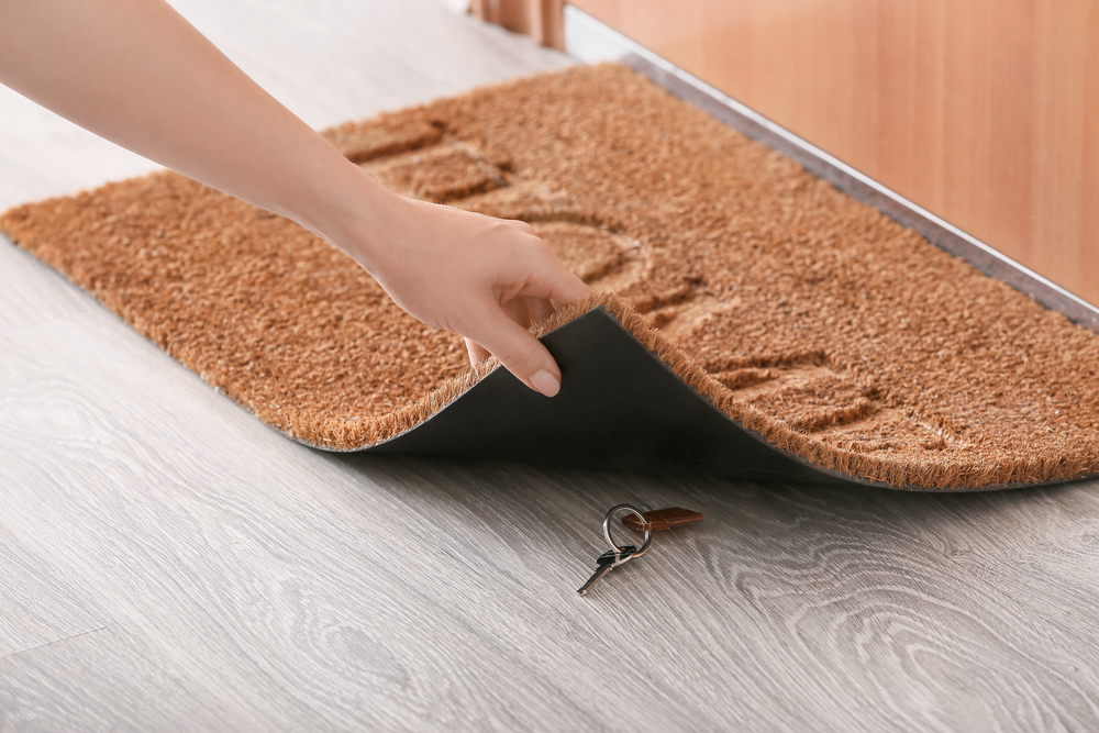 hiding spare key underneath a brown welcome matt