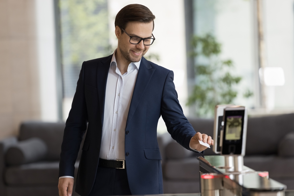 businessman in suit swipe pass card to electronic reader, opening automatic gates, passing security system checkpoint leaves modern office area after working day.