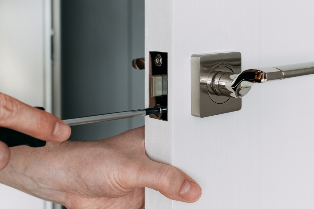 A locksmith repairing a loc on a white residential door